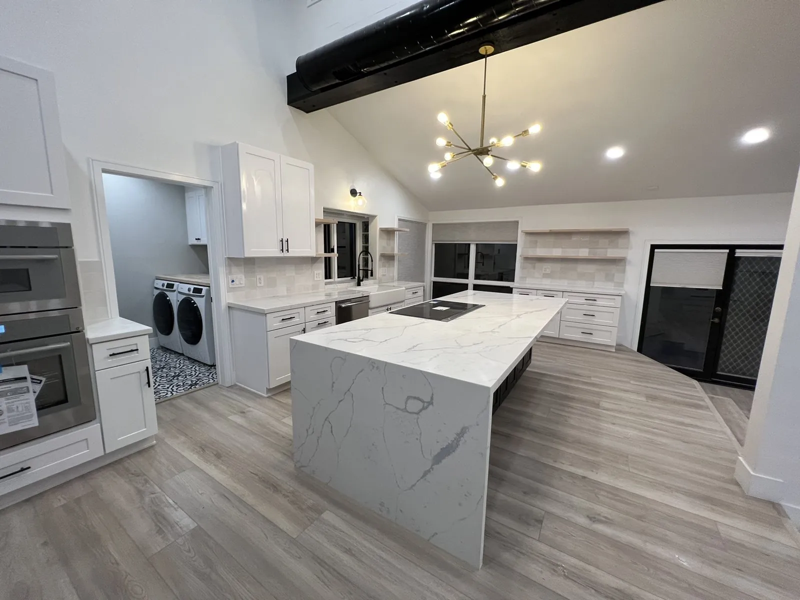 Kitchen remodel with a waterfall quartz island, white shaker cabinets and a vaulted ceiling with exposed beam
