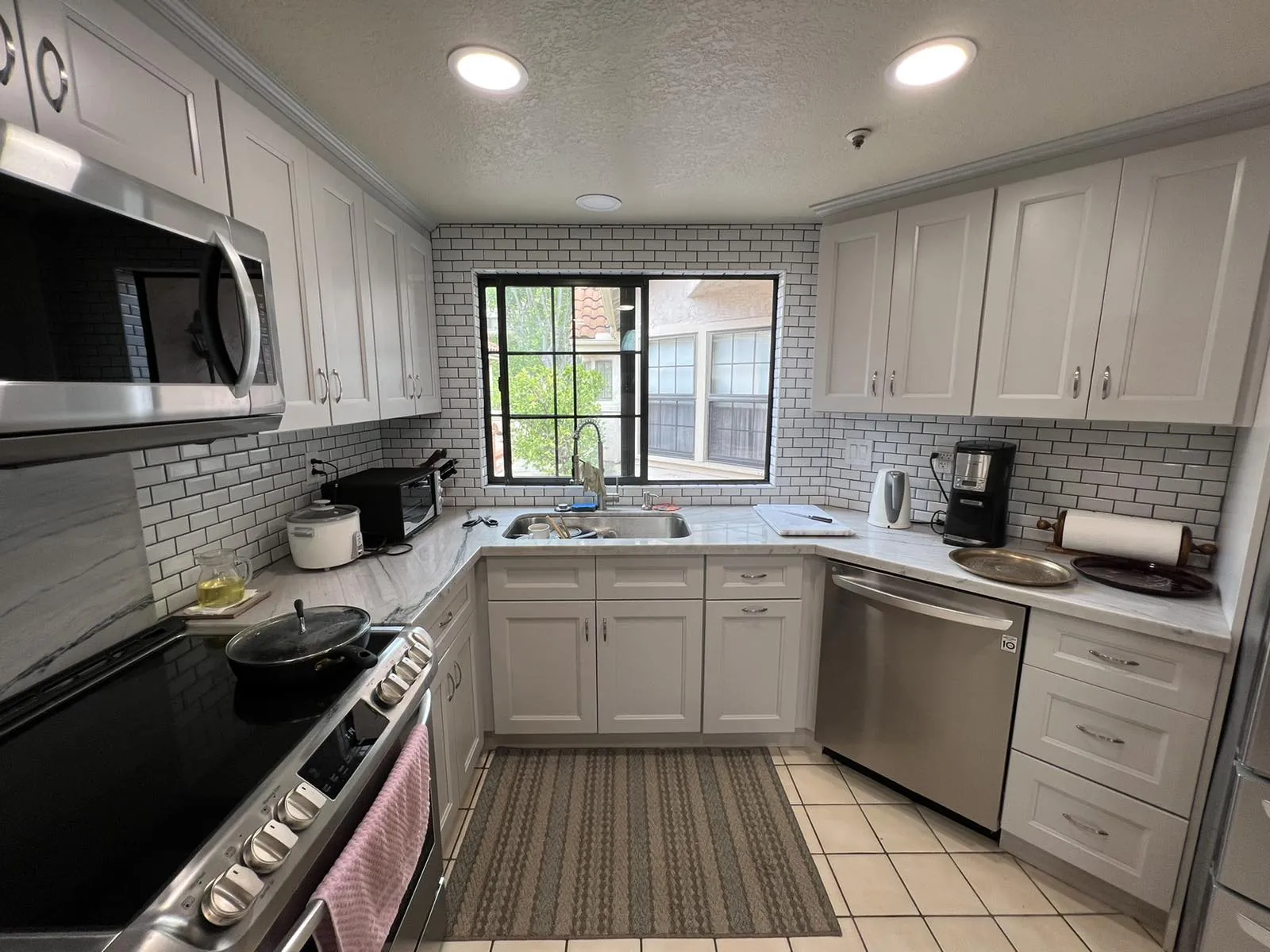 U-shaped kitchen with white shaker cabinets, subway tile backsplash and natural stone countertops